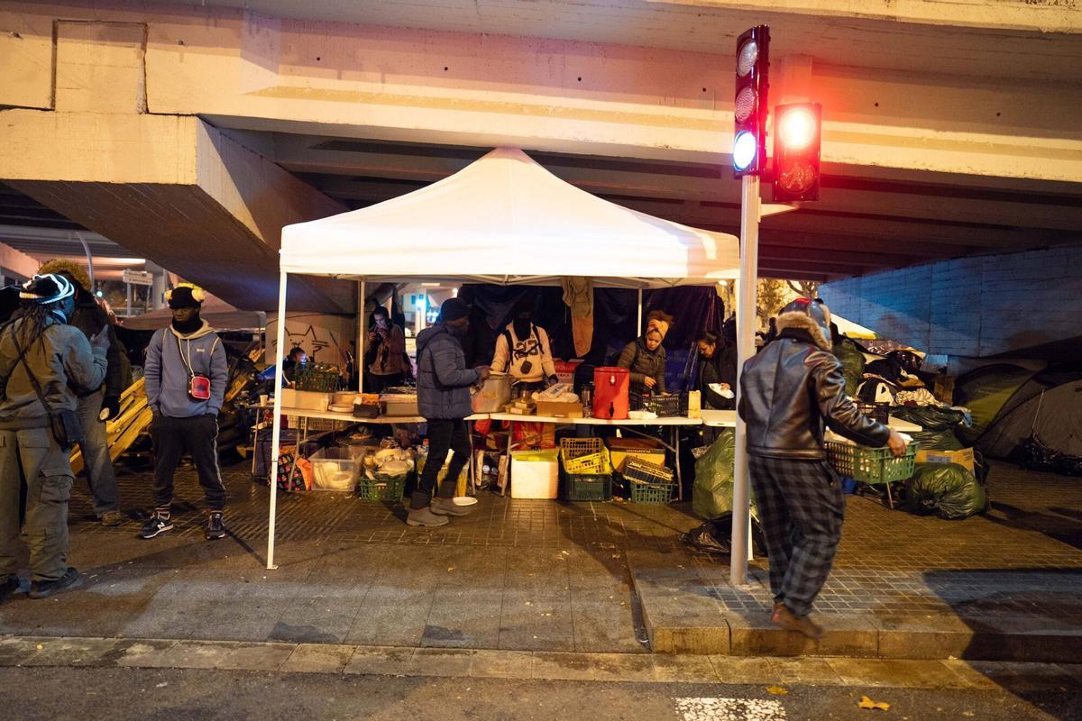 Voluntarios de distintas entidades privadas reparten comida para la cena de Nochebuena bajo la autopista C-31, donde aún duermen decenas de personas desalojadas del antiguo instituto B9
