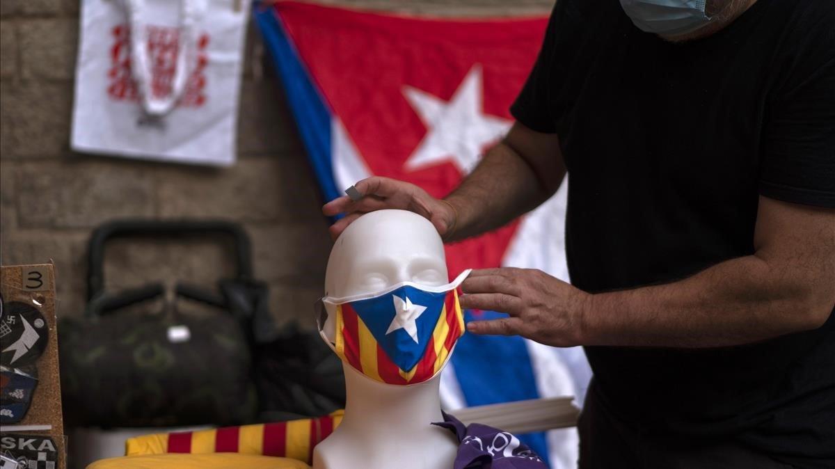 Un vendedor coloca una mascarilla con la bandera independiente a un maniquí.