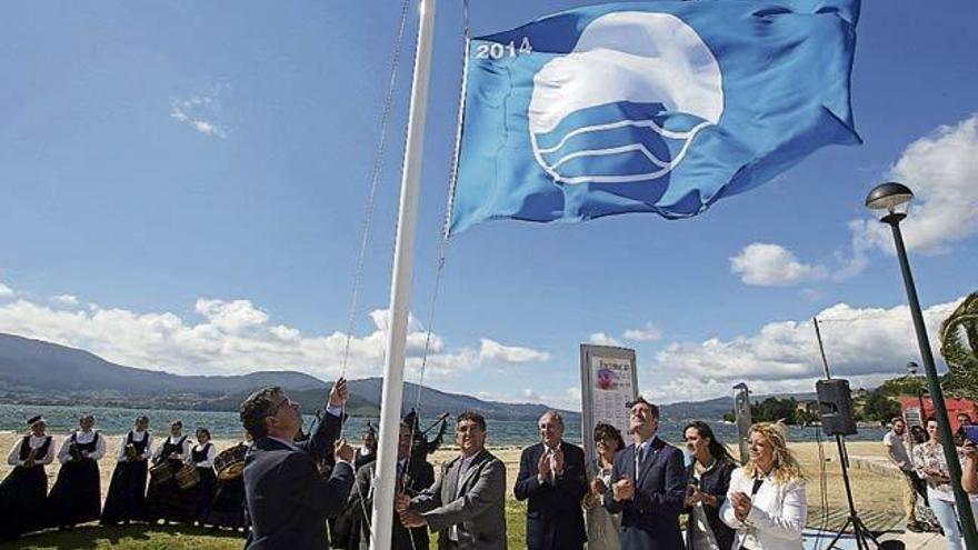 El alcalde Javier Bas iza la bandera azul, ayer en la playa  de Cesantes.  // Marta G. Brea