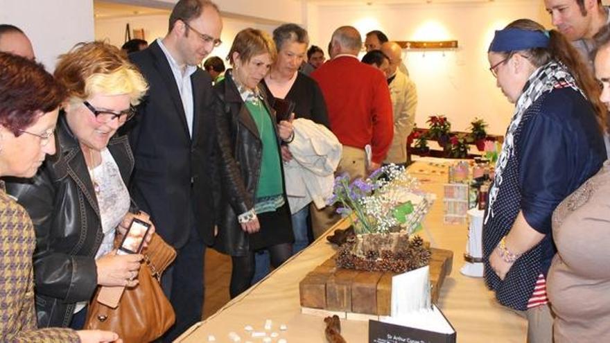 Por la derecha, Yasmine Gijón, Paula Cristina Fernández y Manuel Inclán, mostrando ayer algunos de los diseños a los presentes en la exposición, entre los que estaban el alcalde de Pravia, Antonio de Luis Solar, y Elena Fernández, jefa de calidad de Cogersa (tercero y cuarta por la izquierda).