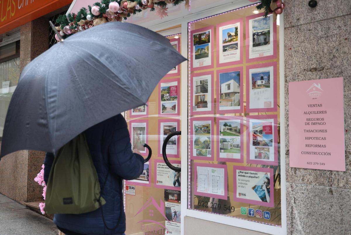 Una persona mirando el escaparate de una inmobiliaria en Vigo.