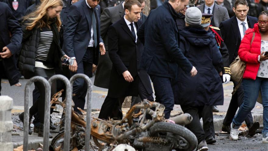 El presidente francés, Macron (c) comprueba los daños materiales ocasionados en las protestas de los llamados &quot;chalecos amarillos&quot;.