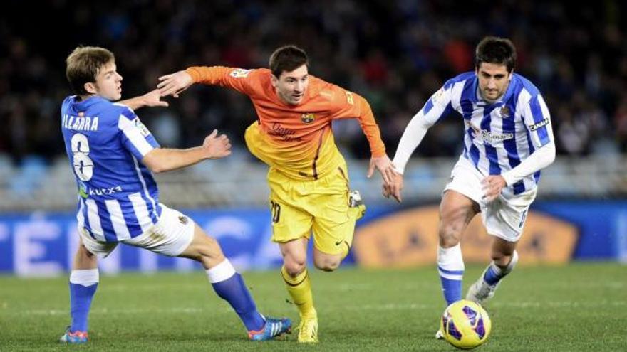 Messi regatea a dos jugadores de la Real Sociedad durante el partido de Liga en Anoeta. // Vincent West