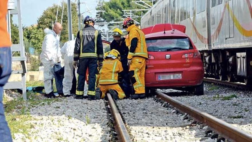 Bomberos y policías, junto al coche que fue arrollado por el tren el pasado jueves en Palma.