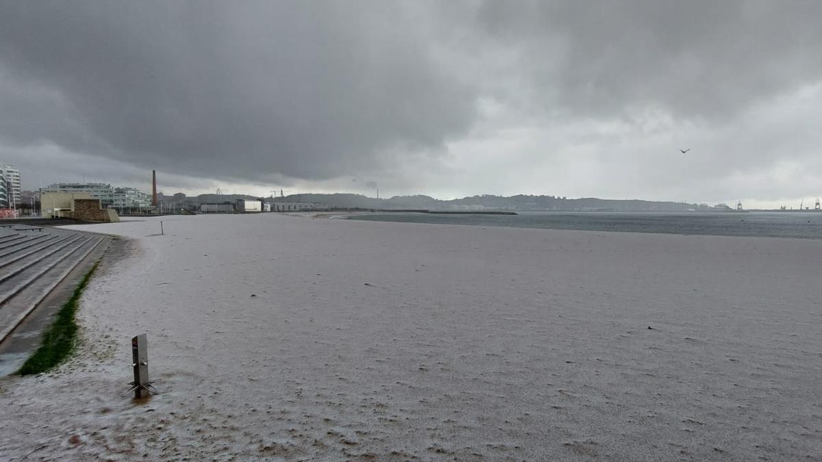 El temporal tiñe de blanco la playa de Poniente de Gijón