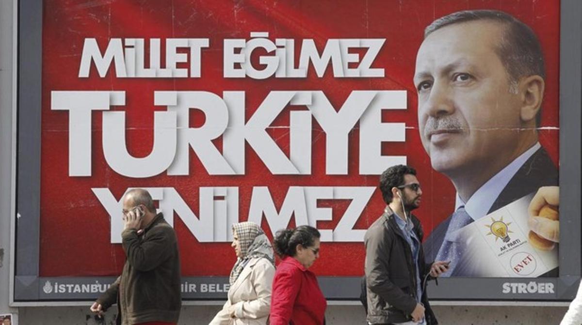 Diverses persones passen davant d’un cartell electoral d’Erdogan, aquest dijous a Istanbul.