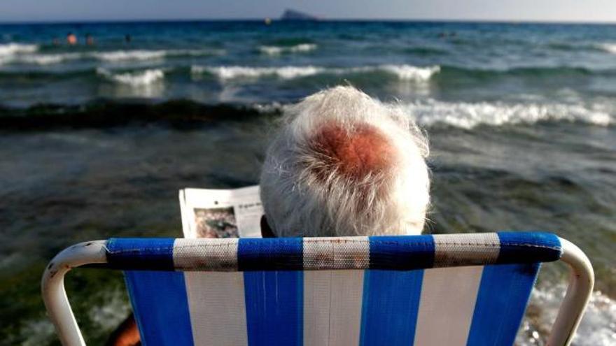 Un turista lee el periódico en una hamaca en la playa de Levante de Benidorm, la capital del turismo de la Comunidad.