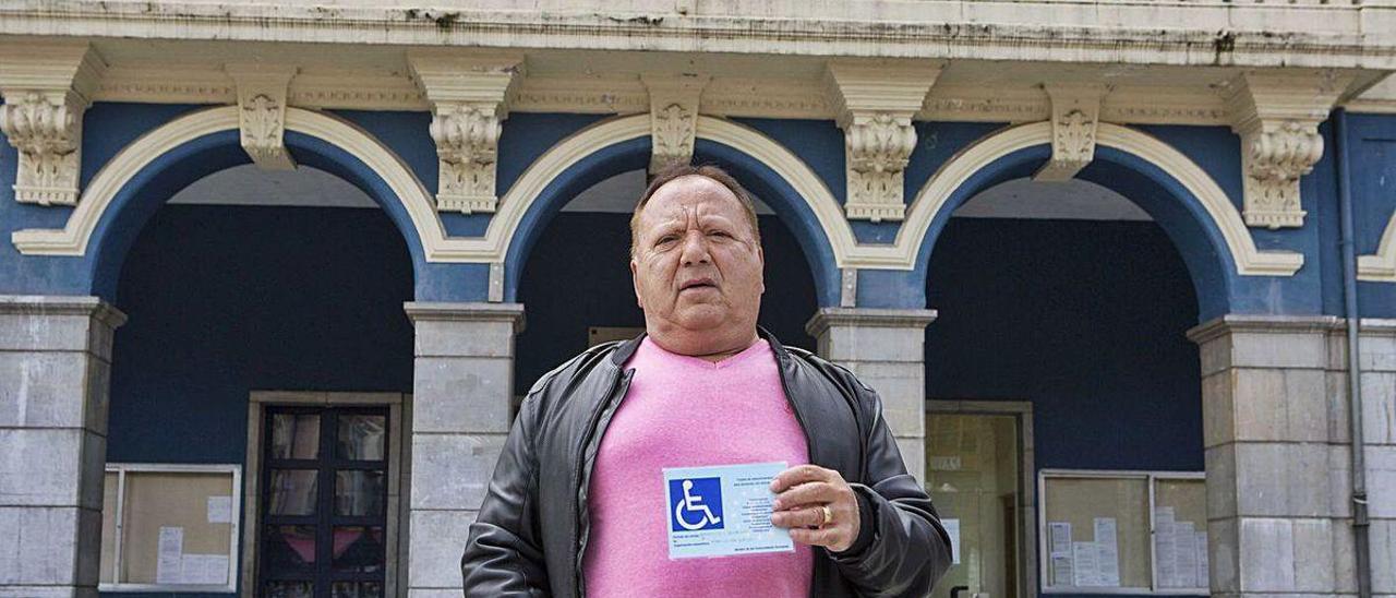 Alfonso Fernández, con la tarjeta de aparcamiento que no puede renovar por las trabas burocráticas, delante del Ayuntamiento de Laviana.