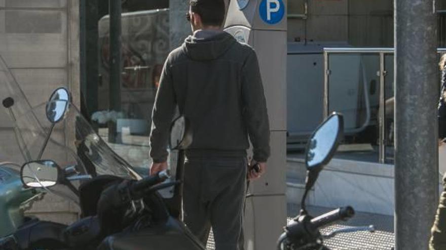 Un conductor sacando el ticket de la O.R.A. rodeado por motos aparcadas en la zona azul.