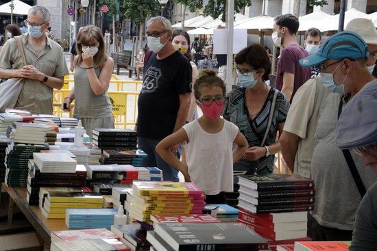 Compradors amb mascaretes mirant llibres al Sant Jordi d'estiu a Girona.