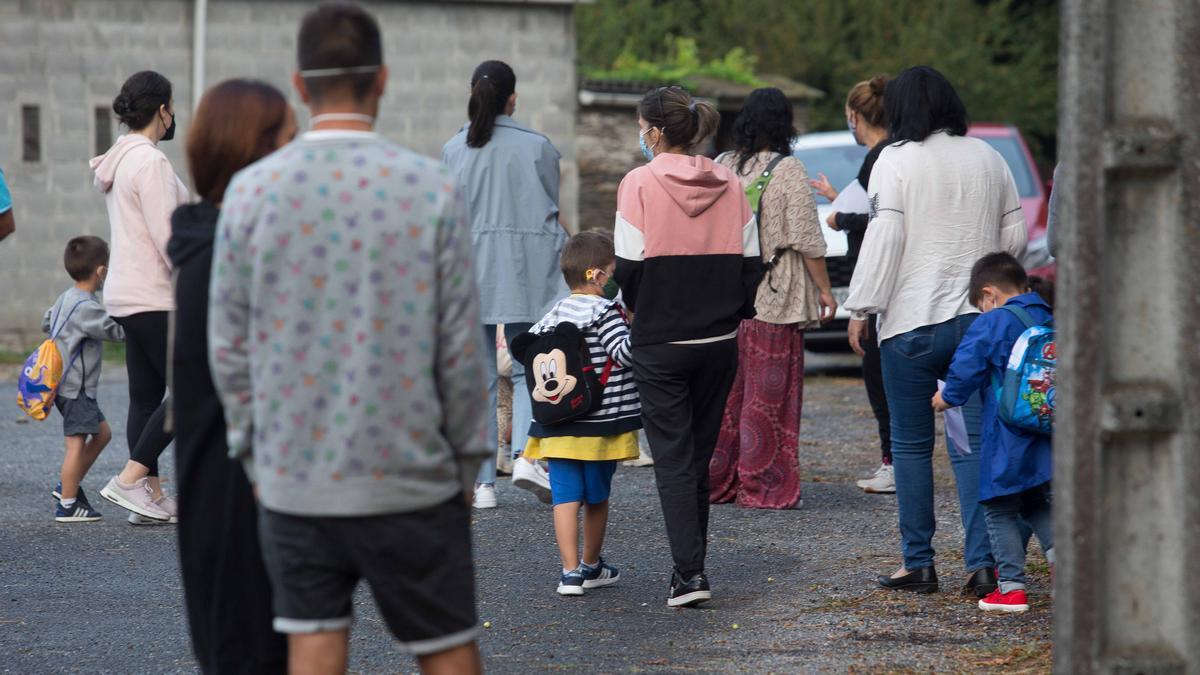 Varios niños acompañados de sus familiares esperan a entrar al colegio.