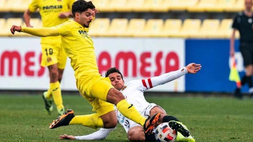 El peñista Marc de Val se lanza a ras de césped para cortar el avance de un futbolista del Villarreal B en el partido que ayer disputaron en el feudo de los amarillos.