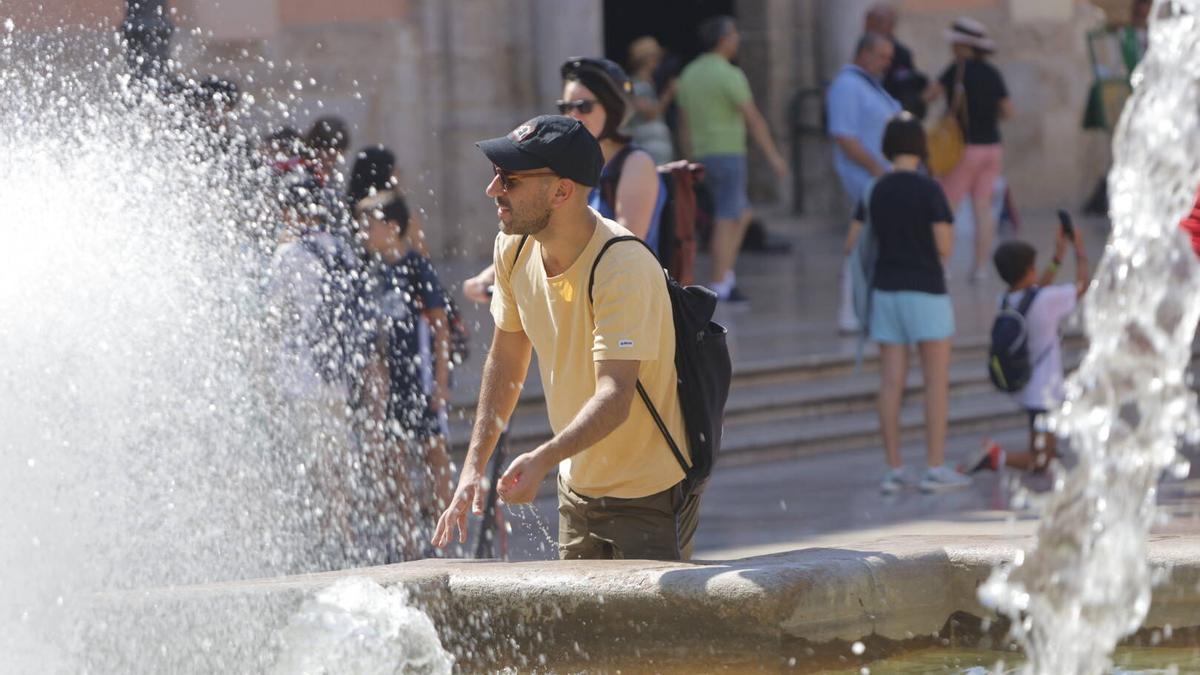 Un hombre se refresca en la fuente de la plaza de la Virgen.