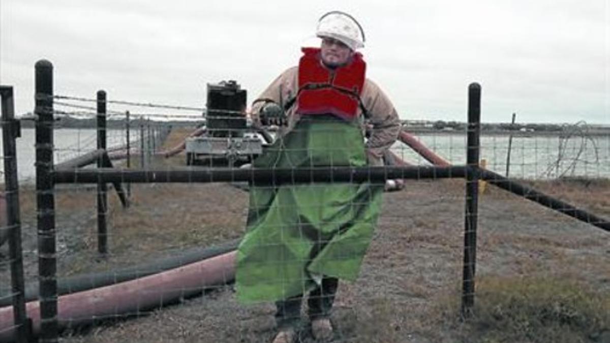 Parón en la producción 8 Un trabajador frente a una balsa de agua usada para el 'fracking' en Kenedy (Tejas).