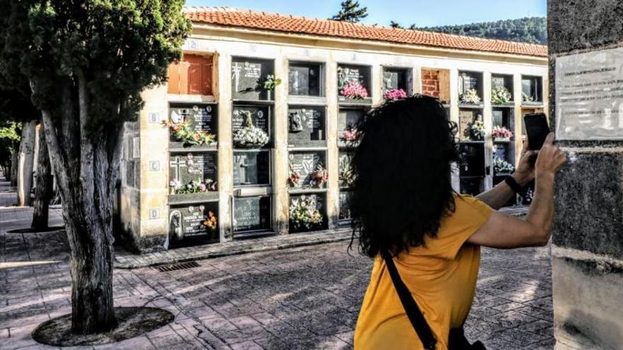 Una mujer fotografía con su móvil una nota informativa colocada en los bloques de nichos afectados.