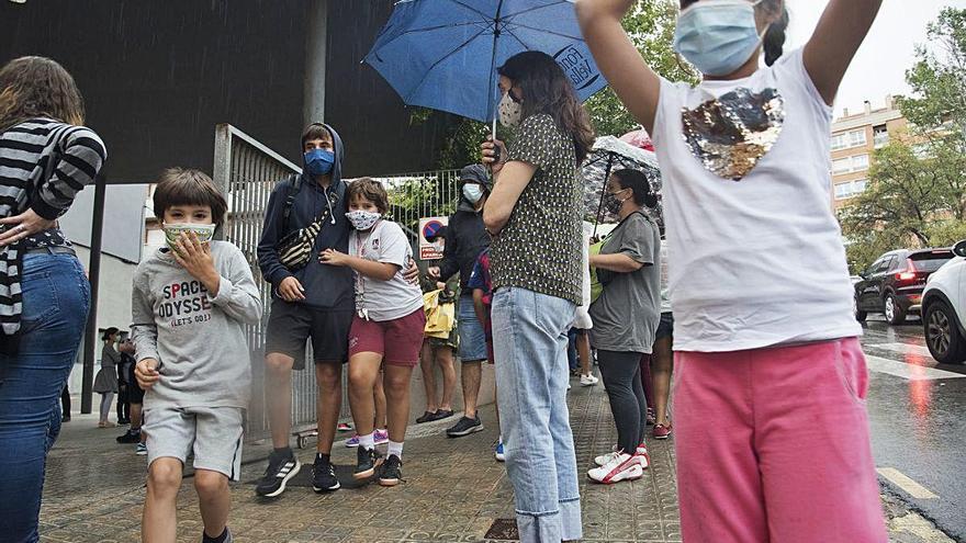 Infants fugint de la pluja a la sortida de l&#039;escola Bages