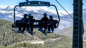 Un telesilla con esquiadores en una pista poco nevada de La Molina este mes de enero.