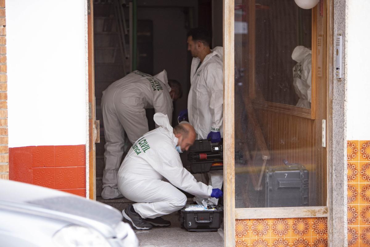 Agentes de Criminalística, en el portal de la finca, preparan los maletines para realizar la inspección ocular de la vivienda.