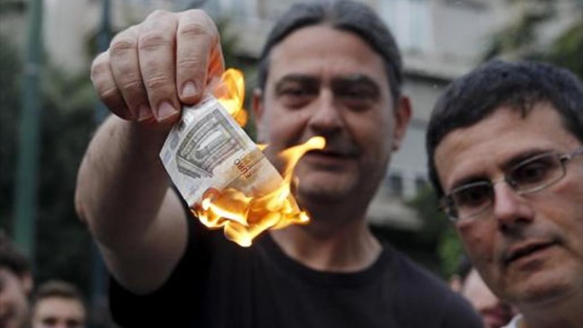 Un manifestante anti-austeridad  quema cinco euros en Atenas.