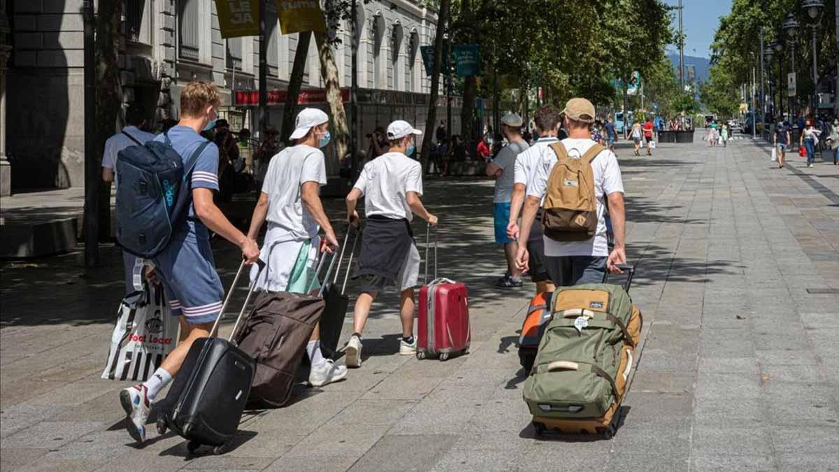 La entrada de turistas en España cae en junio un 97,7%. En la imagen, un grupo de turistas suizos, en Portal de l’Àngel, camino del aeropuerto.