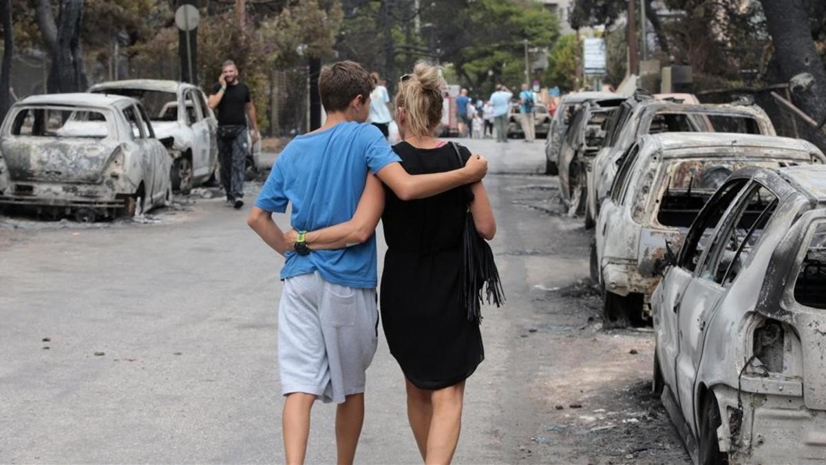 Una paraje camina junto a varios vehículos calcinados en una calle de Mati.