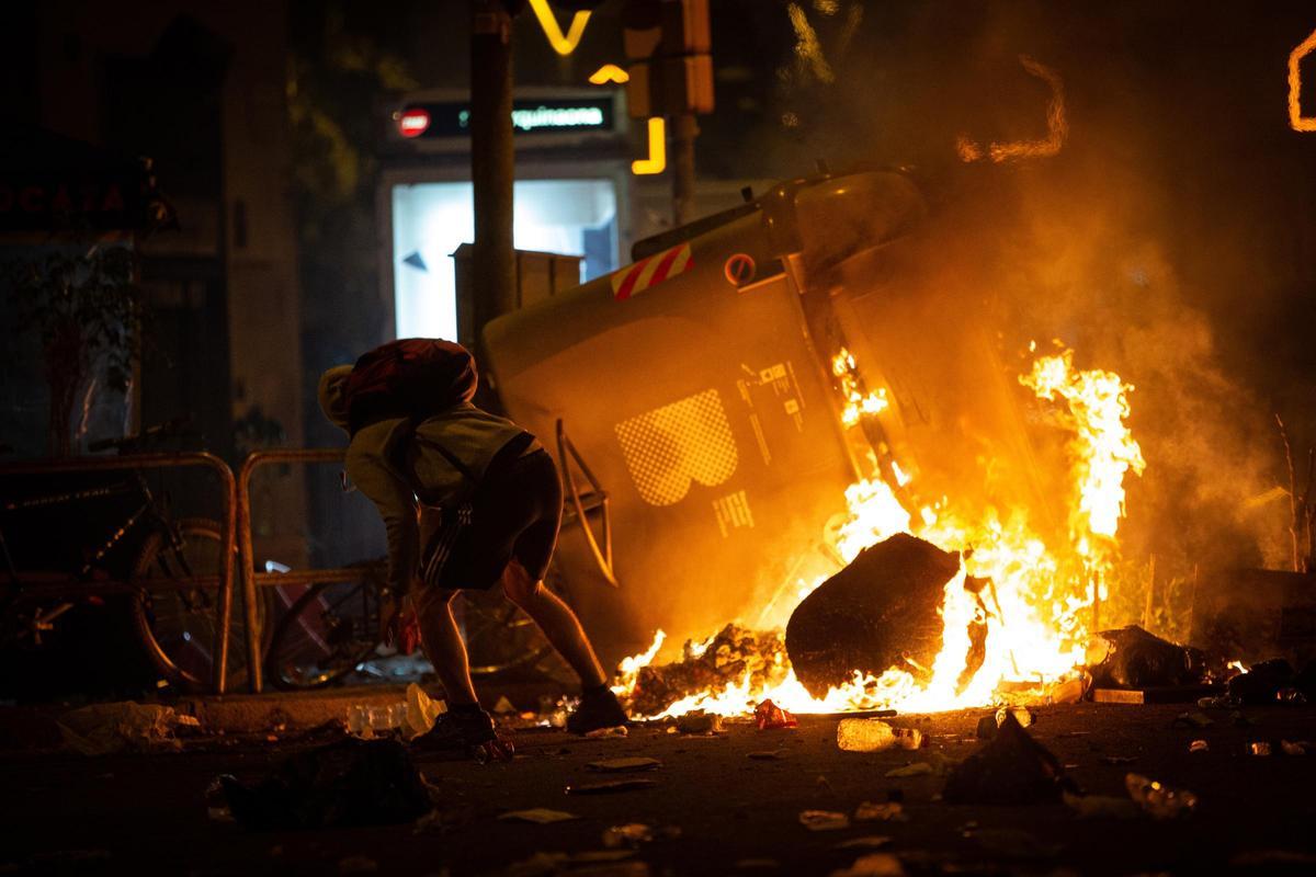 Un manifestante frente a un contenedor que arde durante los disturbios en la Plaza de Urquinaona, en Barcelona a 18 de octubre de 2019.