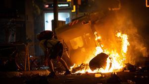 Archivo - Un manifestante frente a un contenedor que arde durante los disturbios en la Plaza de Urquinaona, en Barcelona a 18 de octubre de 2019.