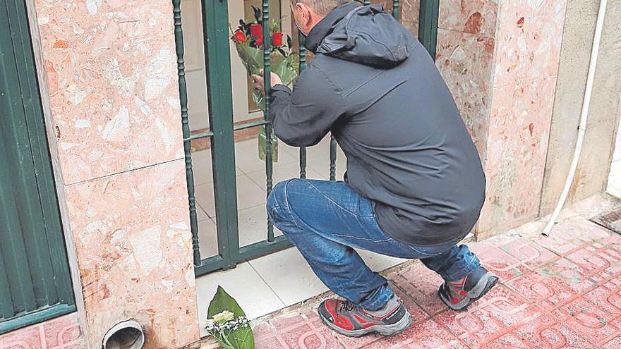 Allegados de la víctima colocan flores en el portal del domicilio