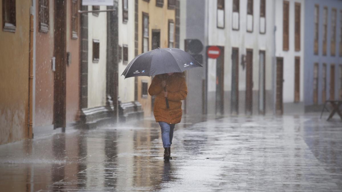 Una mujer intenta cubrirse de la lluvia fuerte con su paraguas