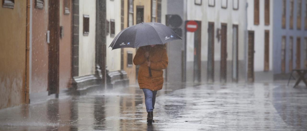 Una mujer intenta cubrirse de la lluvia fuerte con su paraguas