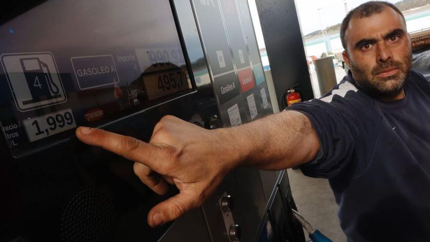 Jorge García muestra el precio del litro de gasoleo en una estación de servicio de Corvera. A la derecha, gasolinera de Proaza que vende la gasolina de 95 a más de 2 euros, como figura en el rótulo luminoso.