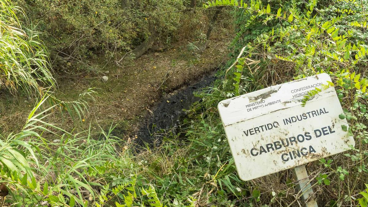 Un cartel que avisa del vertido de la empresa Carburo del Cinca al río.