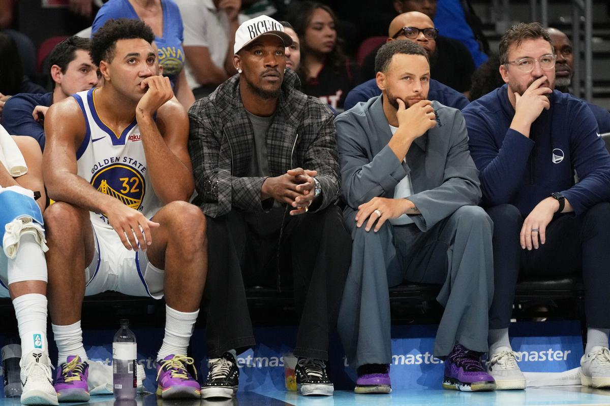 Trayce Jackson-Davis, Jimmy Butler y Stephen Curry, de los Golden State Warriors, en la pista de Miami Heat