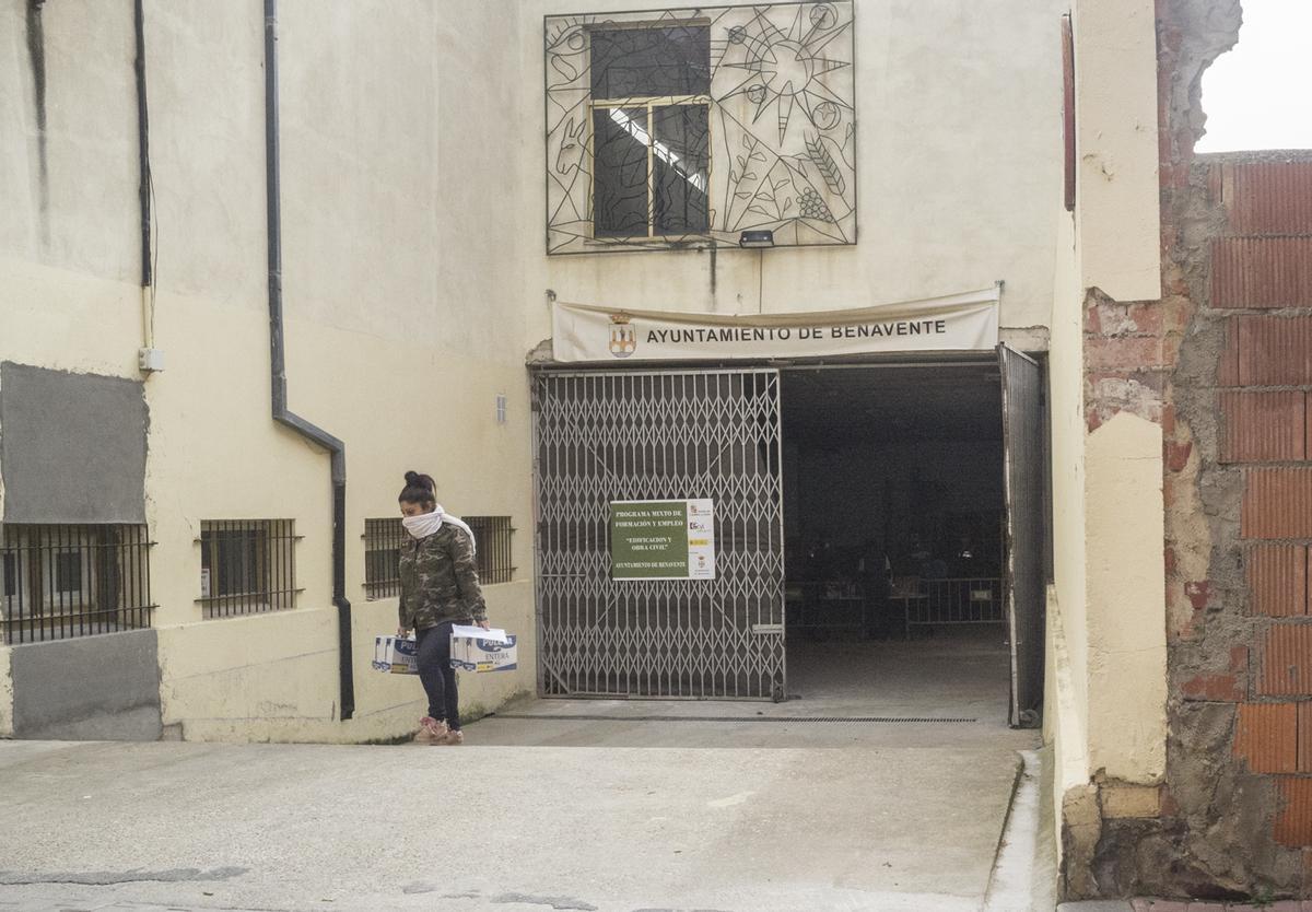 Una mujer saliendo con leche del almacén municipal de alimentos durante la pandemia.