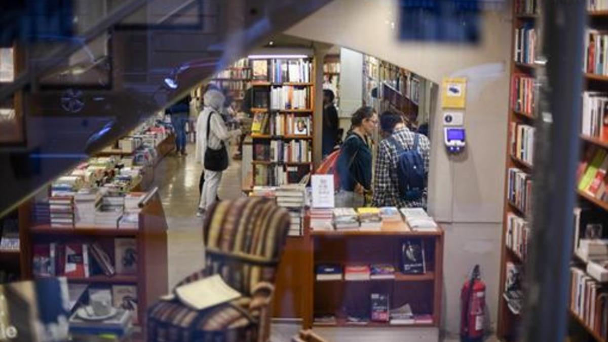 VENTAS DOMINGUERAS3 La mayoría de las grandes librerías del centro de Barcelona estaban abiertas ayer. Junto a estas líneas, interior de Laie. A la izquierda, la Casa del Libro de Rambla de Catalunya. Arriba, decenas de flores decoran la fachada