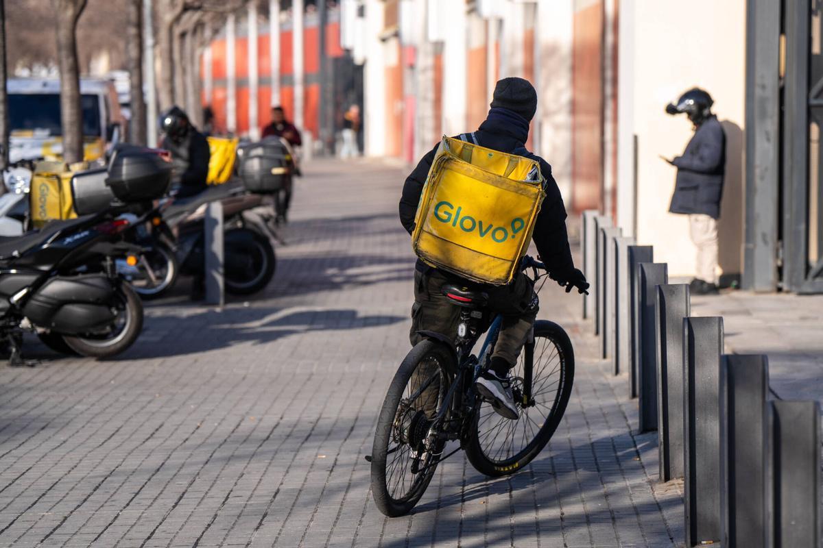 Repartidores de comida a domicilio de la empresa Glovo esperan, recogen y reparten comida en el centro comercial La Maquinista.