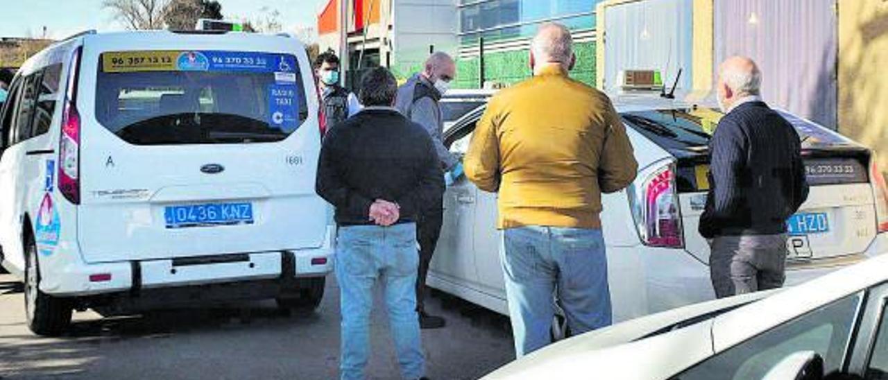 Varios taxistas esperan fuera de sus coches en una parada en València. | G. CABALLERO