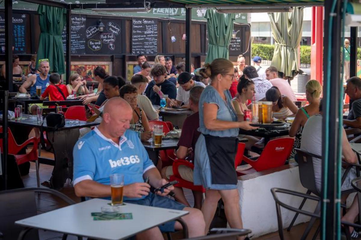 Un bar lleno de turistas, con una camarera trabajando, en la zona turística de Salou (Tarragonès).