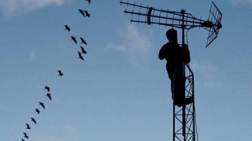 Un operari revisa una antena de telefonia mòbil.