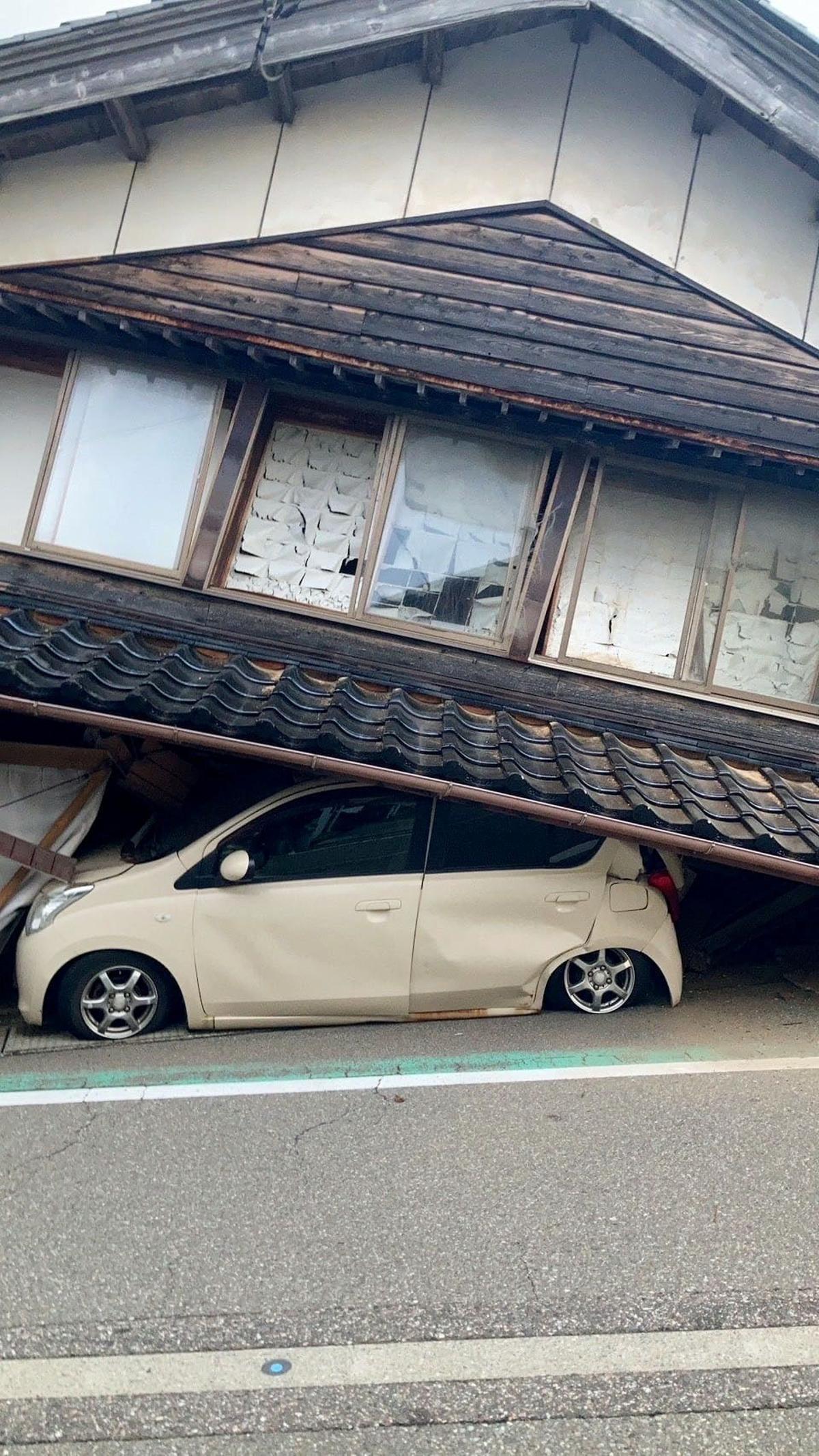 Un automóvil queda atrapado debajo de una casa derrumbada por el efecto de un terremoto, en la ciudad de Shika, prefectura de Ishikawa, Japón