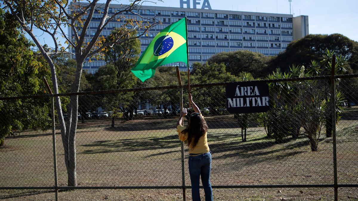 Una simpatizante de Bolsonaro coloca una bandera de Brasil ante el hospital.