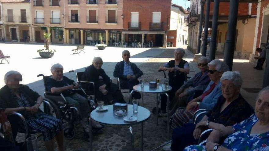 Los mayores de la residencia descansan en la Plaza Mayor de Villalpando tras una salida.