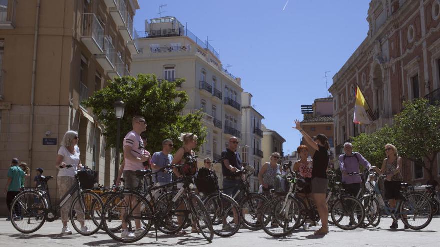 Un grupo de turistas recorre València en bicicleta.