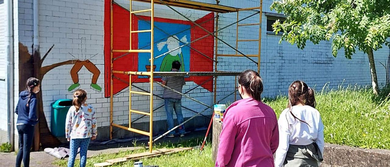 Un grupo de alumnas observa a evolución do mural do colexio.