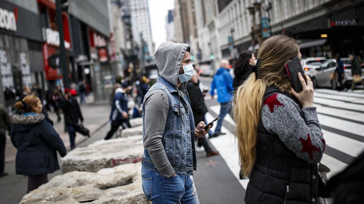 zentauroepp52759518 a pedestrian uses his phone while wearing a face mask in new200312193443