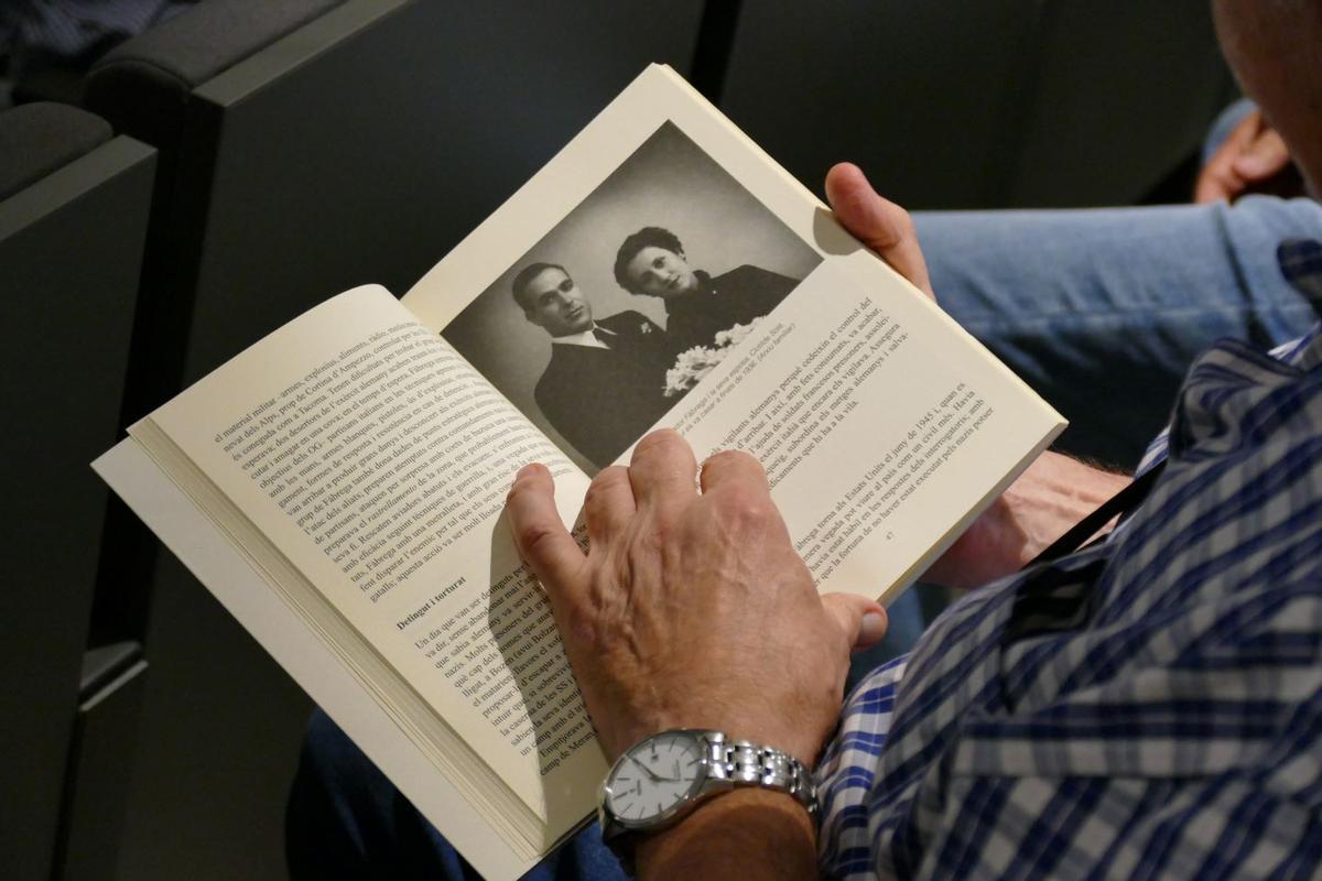 Un dels assistents a l'acte fullejant el llibre que inclou fotografies de tots els absents biografiats.