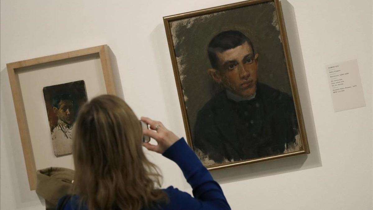 Una mujer observa en el Museo Picasso un Autorretrato del pintor malagueño de 1896 y un Pablo Picasso de Ramon Riu.