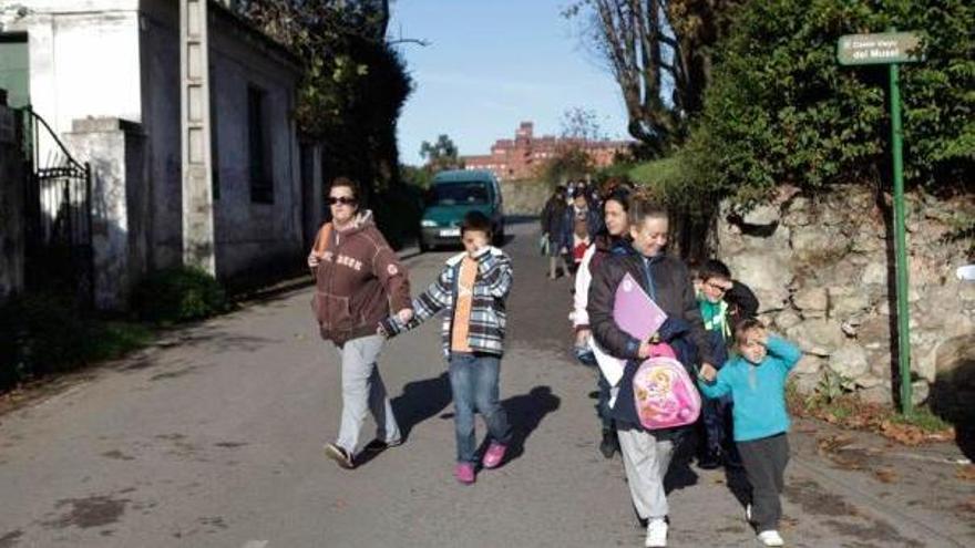 Niños transitando por el camino de Jove sin acera acompañados por familiares para ir al colegio.