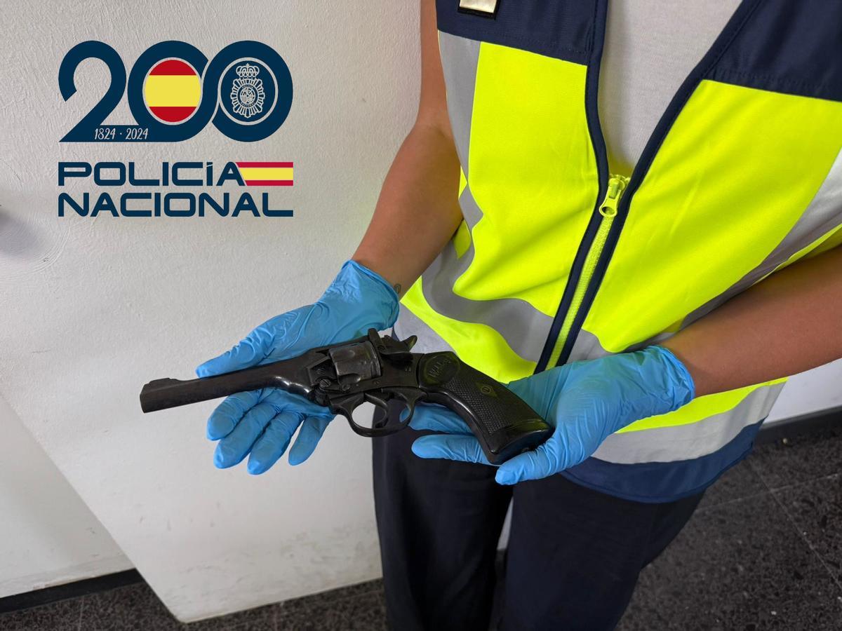 Una agente sostiene el revólver del 38 intervenido al conductor de un coche.