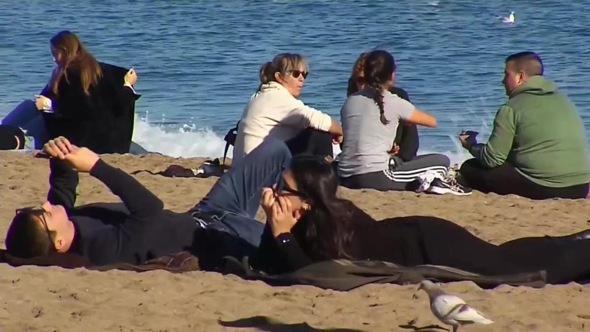 Visitantes ya abrigados en las playas de Barcelona, en un día de temperatura otoñal.